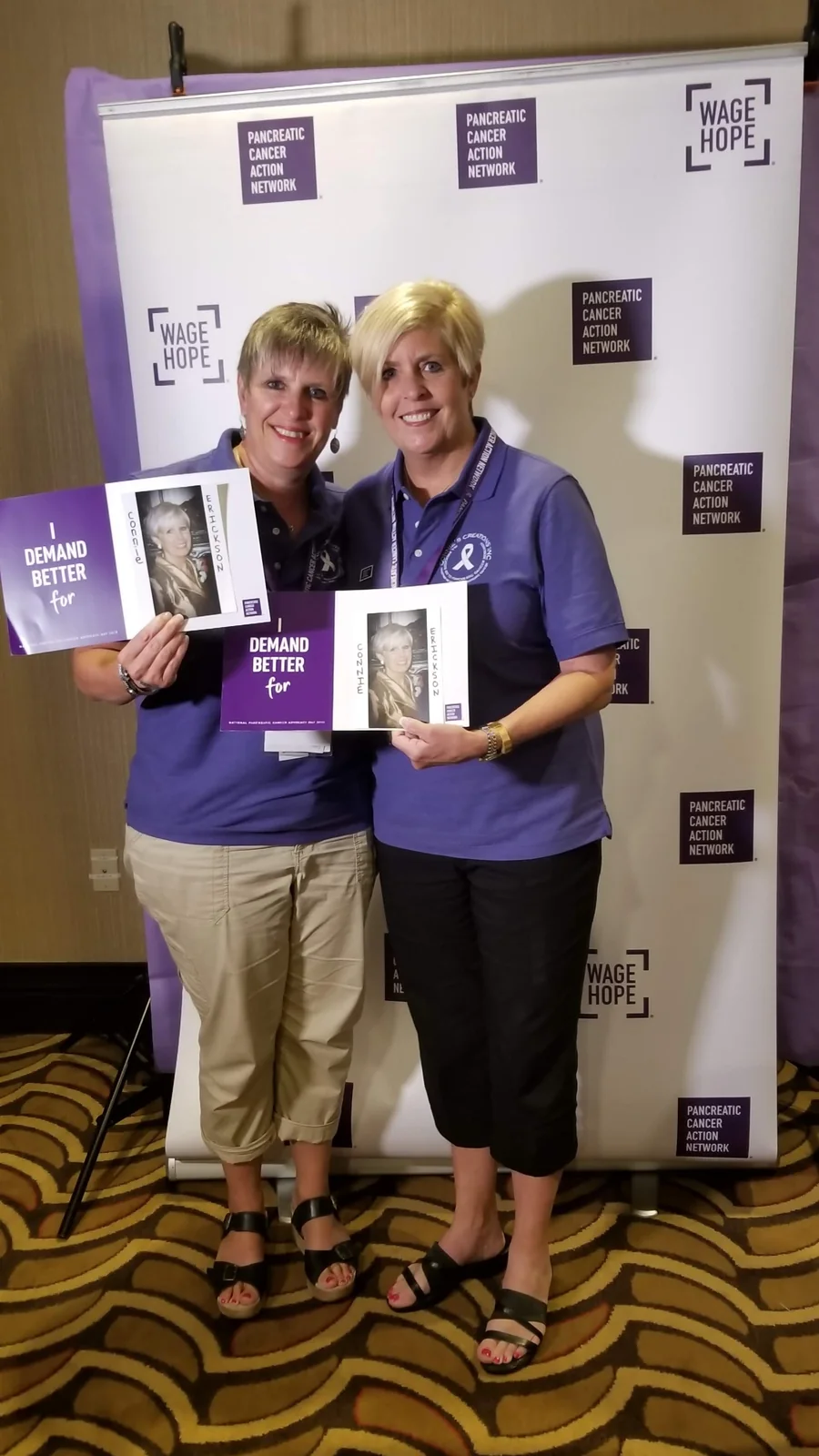 Two supporters holding PanCAN tribute signs with photos of Connie Erickson