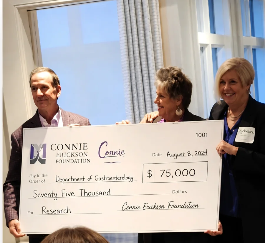 Three representatives holding a Connie Erickson Foundation research check for $75,000