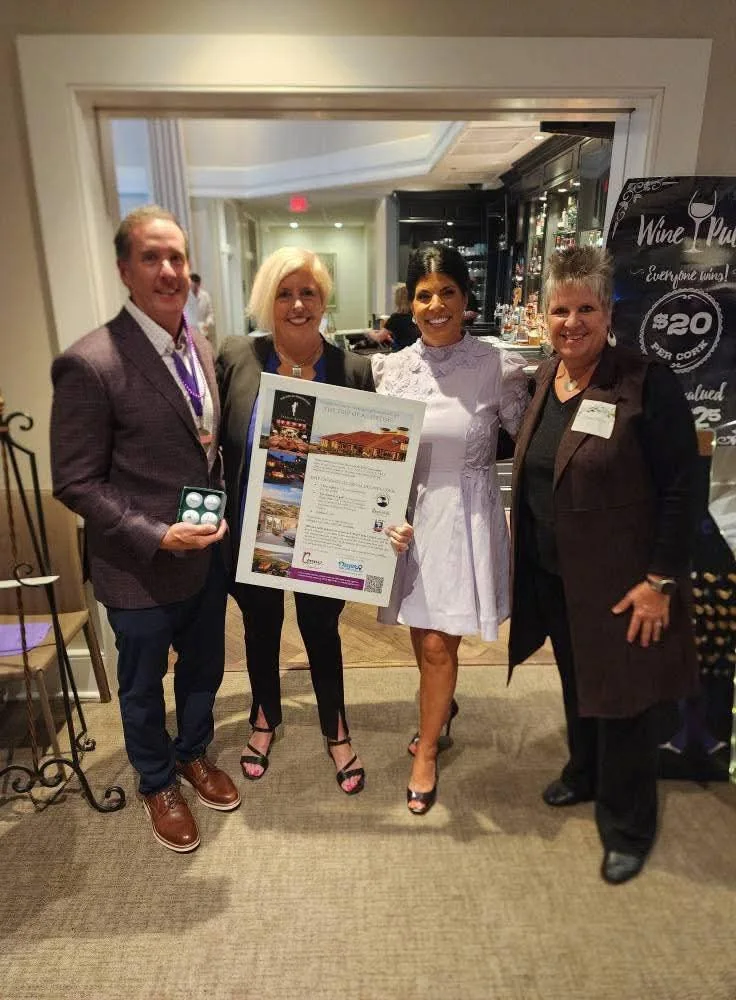 Four Sip & Swirl guests holding a framed prize display beside the wine pull