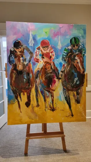 Painting of three jockeys on horseback displayed on an easel at Sip & Swirl